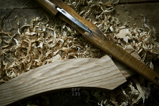 A chisel and wooden object with wood shavings, on a workbench