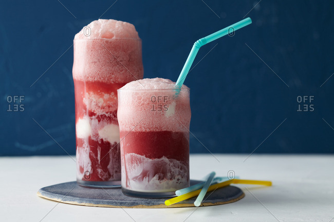 Two berry ice cream floats with colorful straws