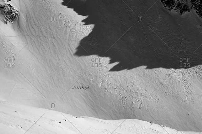 Aerial view of a group hiking single file up a snowy mountain