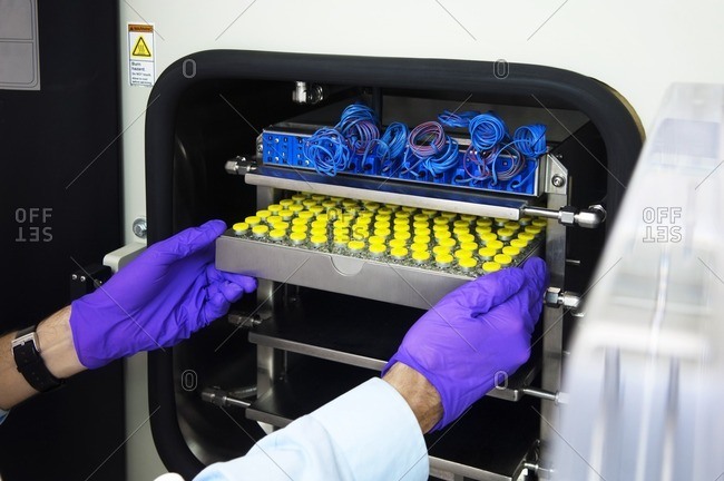 Scientist inserting medical sample tray in machinery
