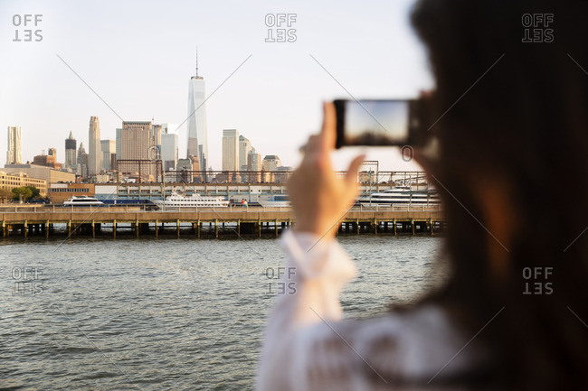 Woman photographing skyline during sunset
