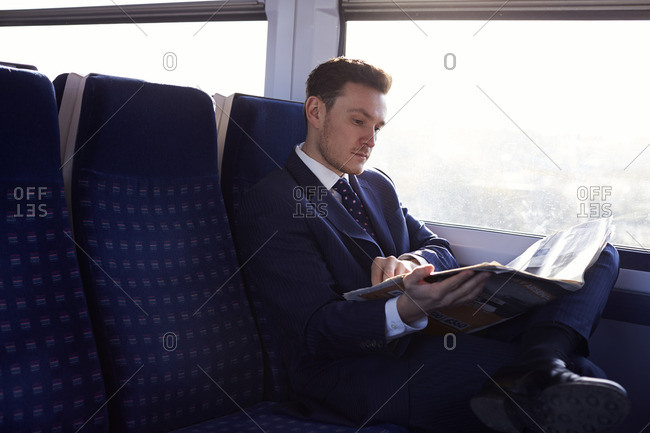 Businessman reading newspaper on train