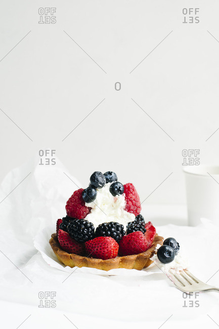 Fresh berry and cream tartlet with a bite missing