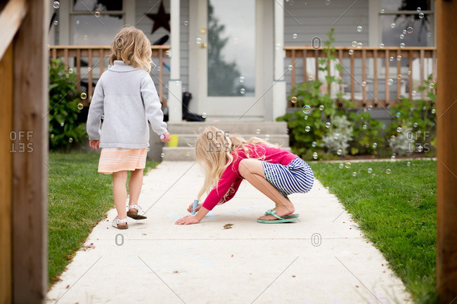 Girl drawing on sidewalk by house