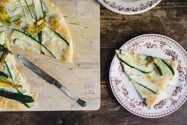 Slices of squash blossom, zucchini and mozzarella tart served on floral pattern porcelain plates