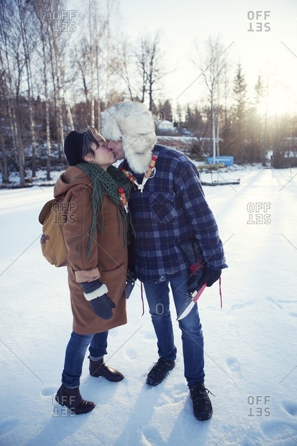 Couple standing in snow kissing