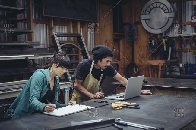 Man and woman working together at a computer in a mechanic shop