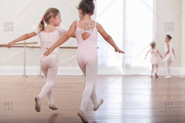 Rear view of girls practicing jump in ballet school