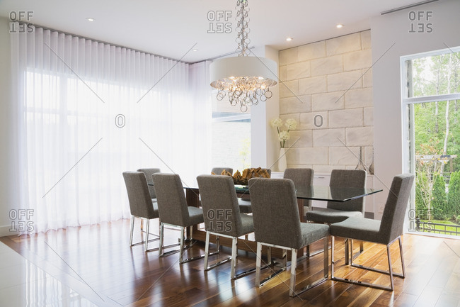 Modern interior design luxury dining room with glass dining table and grey upholstered dining chairs