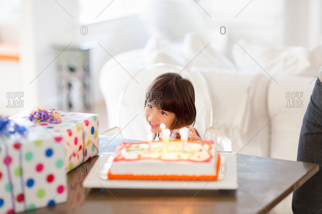 Delighted girl with birthday cake and presents on table