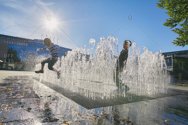 Boys jumping in city fountain
