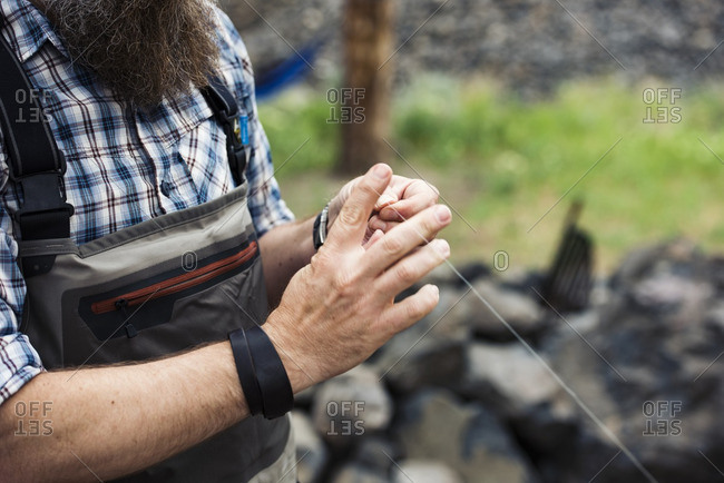 Midsection of mature man holding fishing thread on field