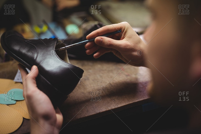 Cobbler painting the shoes in workshop
