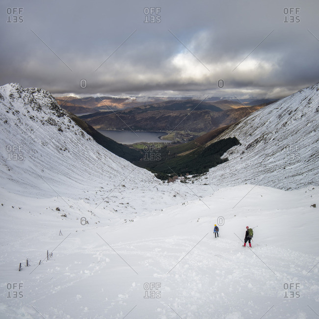 Two people climbing down a mountain in winter