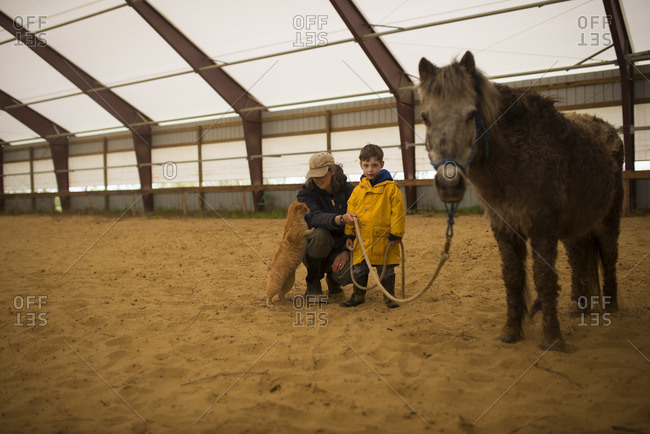 Woman and little boy with a pony and cat in an equestrian arena