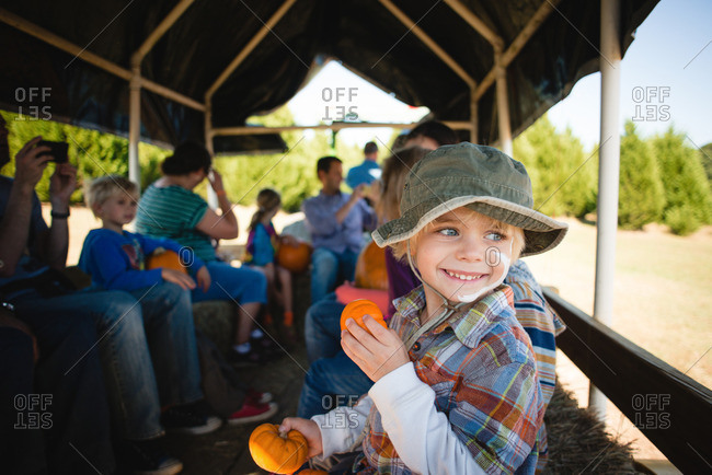 Boy on a hay ride holding small pumpkins