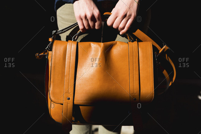 Woman\'s hands holding leather bag, close-up