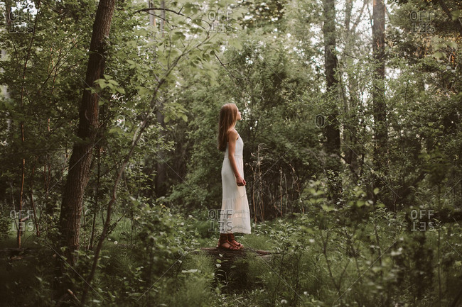 Young woman in a long white dress standing on a log