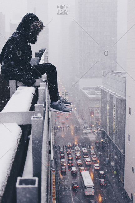 Person sitting on the ledge of a skyscraper in Chicago, Illinois in winter, snow and traffic