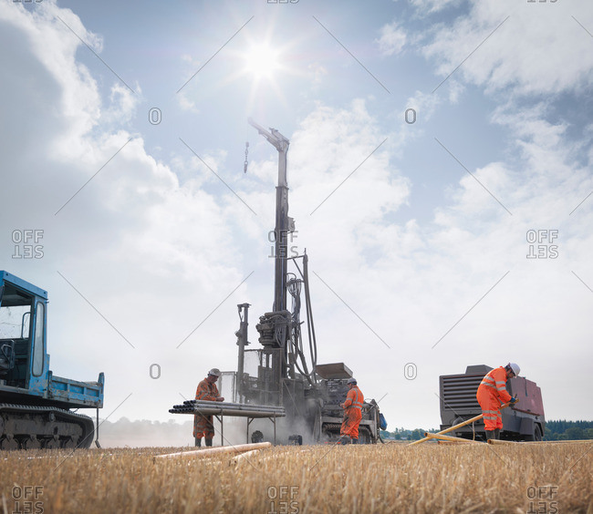 Workers and drilling rig exploring for coal in field