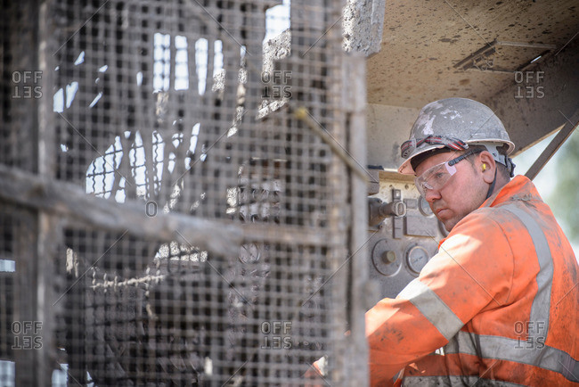 Worker in hard hat operating drilling rig in field