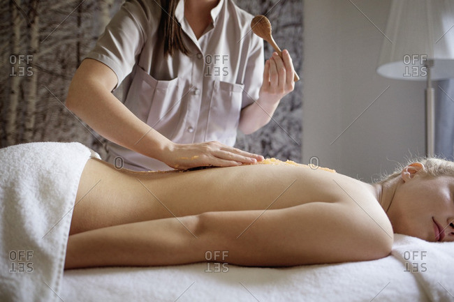 Midsection of massage therapist applying medicine on woman\'s back in spa