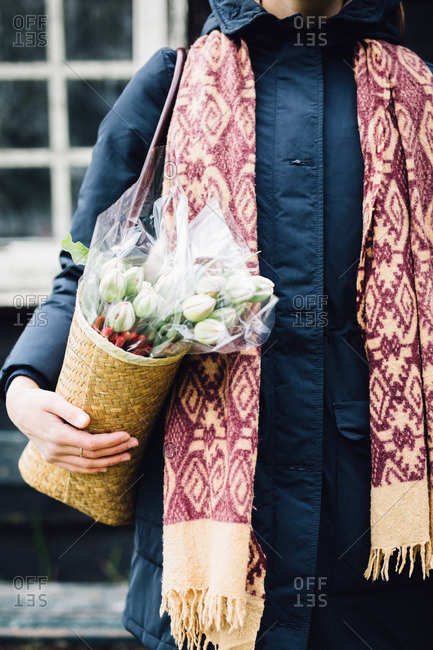 Woman carrying shoulder bag containing bouquet of flowers