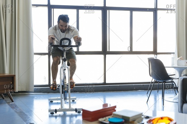 Man riding stationary bicycle in loft apartment