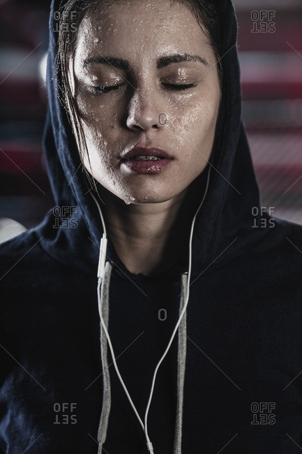 Woman in hooded shirt with sweat on face at gym