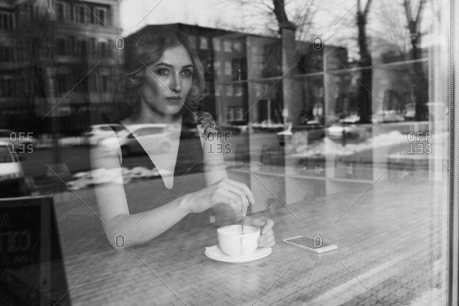 Thoughtful young woman stirring coffee in coffee shop