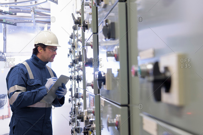 Worker inspecting switch gear in hydroelectric power station