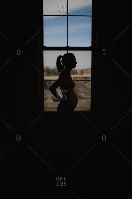 Silhouette of a pregnant woman against a window