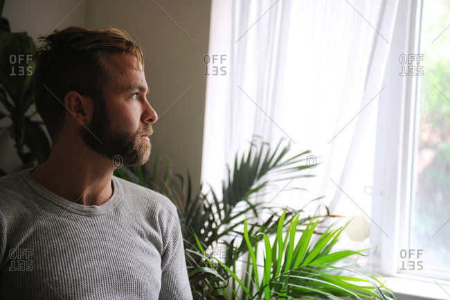 Bearded young man staring out window