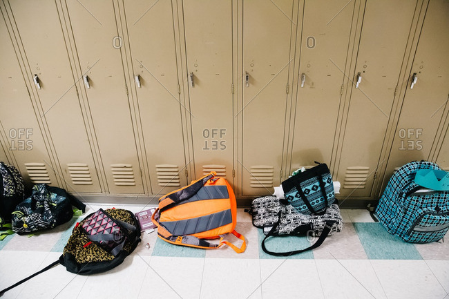 Backpacks sitting in a hallway next to a row of school lockers