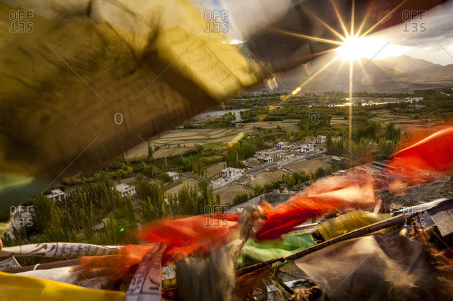 The sun sets over a Ladakhi village outside of Leh, viewed through the flapping prayer flags