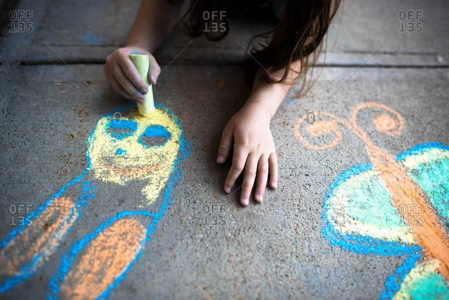 Girl drawing with chalk on sidewalk