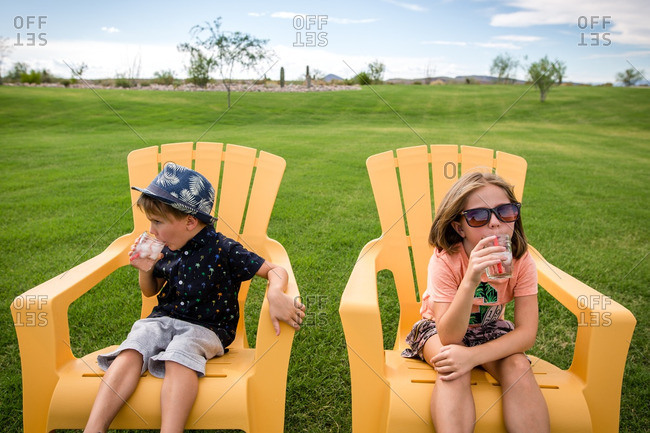 Children sitting on yellow chairs drinking icy drinks