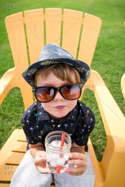 Close up of a boy sitting on a yellow chair drinking an icy drink