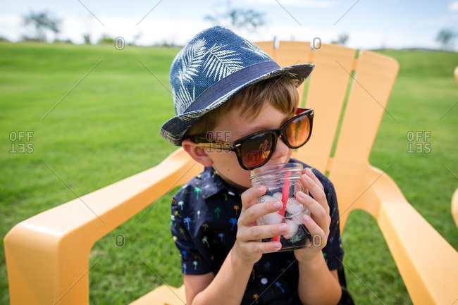Boy sitting on yellow chair drinking an icy drink