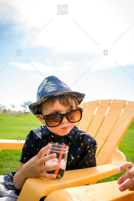 Boy drinking an icy drink while sitting on a yellow chair