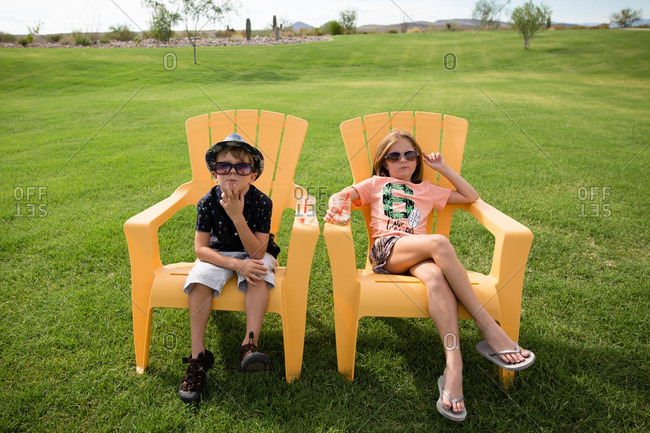 Children relaxing on yellow chairs drinking icy drinks