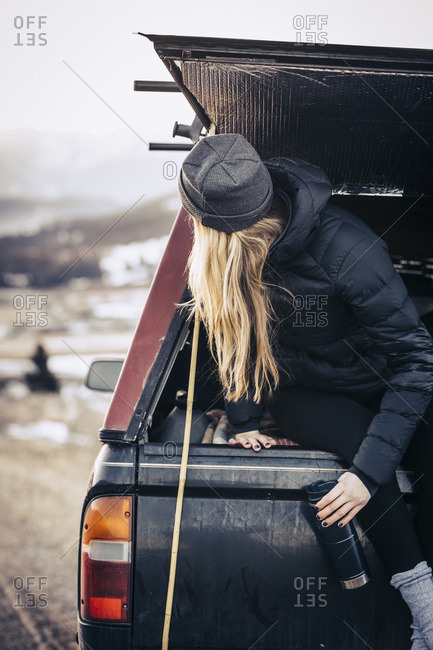 A woman looking out from the rear hatch of a pick up truck camper