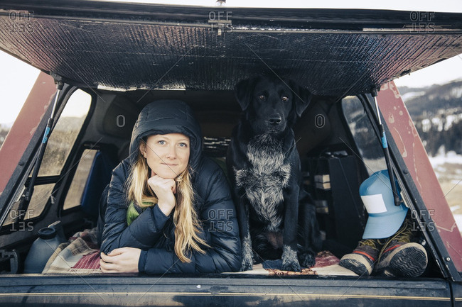 A woman and her dog looking out from the rear hatch of a pick up truck camper