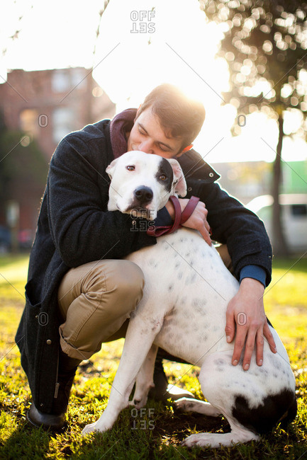 Man hugging dog in park