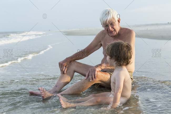 Grandfather sitting with toddler on the ocean shore