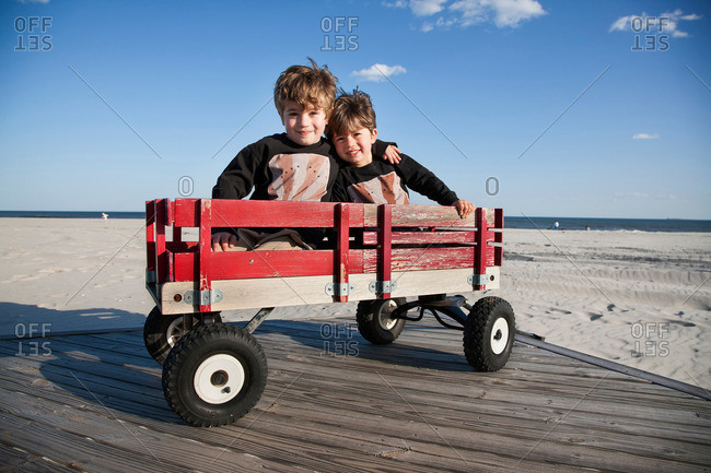 Two brothers in cart on beach with arms around each other
