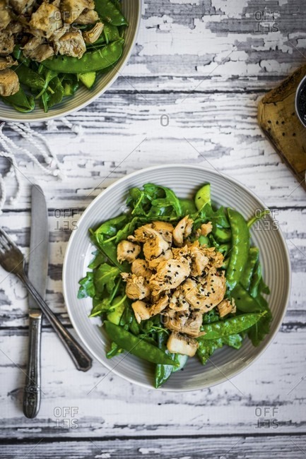 Grilled chicken with spinach, rocket and peas on rustic wooden surface