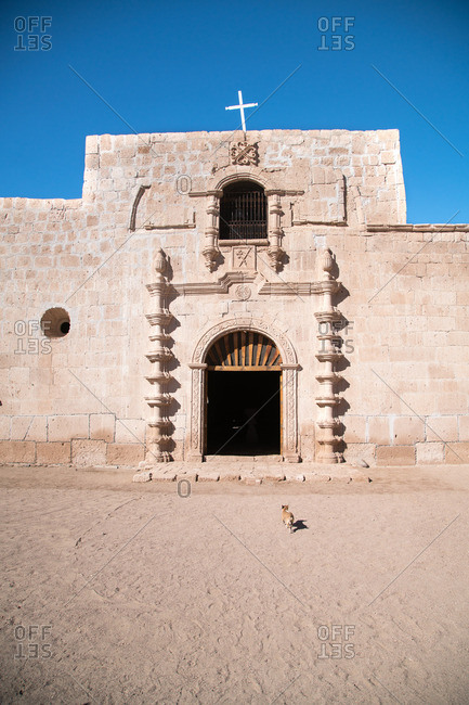 Dog walking toward entrance to historic mission in Mexico