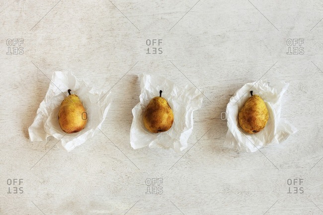 Overhead view of pears in wax papers arranged on wooden table