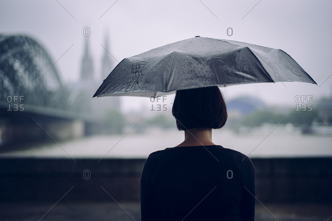 Germany- Cologne- back view of woman with umbrella on a rainy day